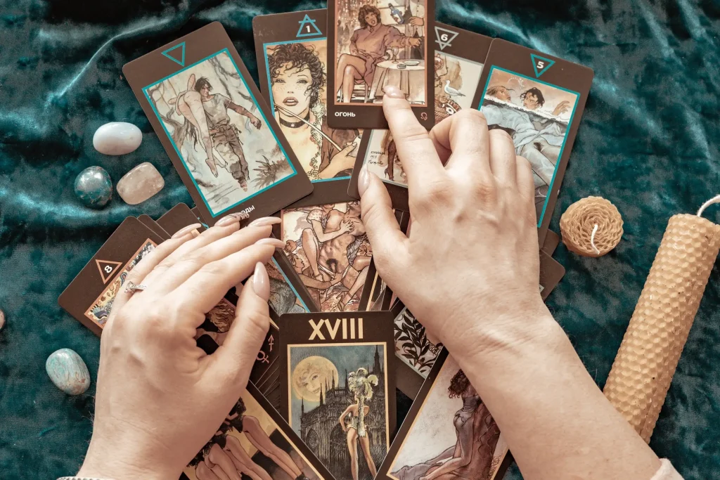 Aerial view of the tarot card with young woman hand with candles and rocks on the table.